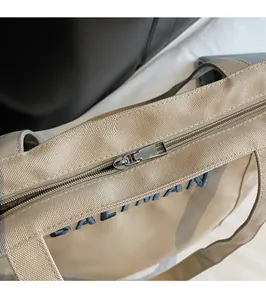 Detail of silver metal zipper and blue brand embroidery on beige canvas tote bag