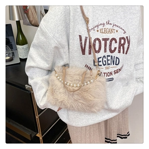 Dettaglio della borsa in peluche beige con manico di perle e tracolla rimovibile