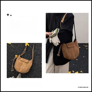 Detail view of brown suede bucket bag with white contrast stitching and shoulder strap