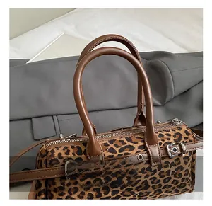 Detailed macro view of leopard print boston bag with brown leather handles and silver hardware