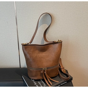Détail du sac seau vintage en cuir marron avec fermeture éclair et longues franges