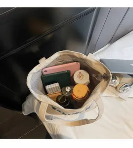 Interior view of large beige canvas tote bag showing storage space for tablet and bottle