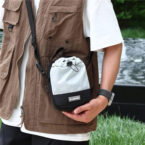 Outdoor crossbodytas met treksluiting gedragen met een bruin vest met zakken