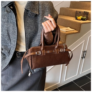 Detail view of coffee suede Boston bag with vintage buckle straps and textured finish