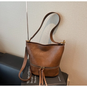 Vue détaillée du sac seau en cuir marron avec glands rétro et fermetures en bronze