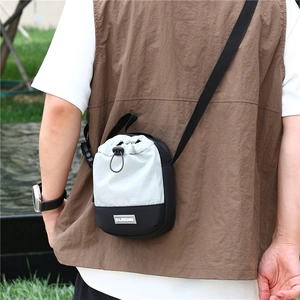 Outdoor crossbodytas met trekkoordsluiting en compact nylon ontwerp getoond op een persoon