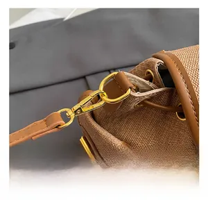 Detail of high-quality gold metal hook and brown woven texture on a vintage crossbody bag