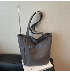 Close-up of Baliman dark grey canvas tote bag with blue embroidered logo and long shoulder strap