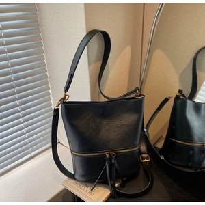 Détail du sac seau vintage noir avec fermeture éclair dorée et pompons élégants