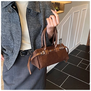 Close-up of deep brown suede cylinder bag with leather handles and metallic buckle details