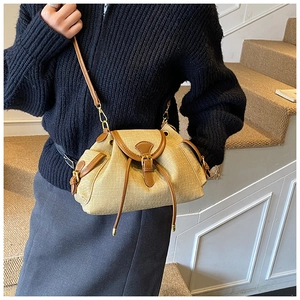 Detail view of vintage beige straw bucket bag with dark brown leather trim and gold clasp