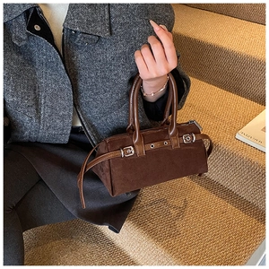 Detail of dark brown vintage cylinder bag with suede texture and silver buckles