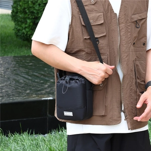 Detail van een zwarte nylon outdoor crossbodytas met trekkoordsluiting en een logo