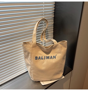 Detail of blue embroidered logo on a beige canvas tote bag with light and shadow