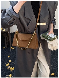 Détail du sac bandoulière en cuir marron avec chaîne dorée et logo sur le rabat