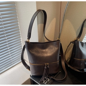 Détail d'un sac seau vintage en cuir marron avec fermeture à franges et éclairage tamisé