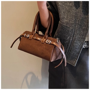 Detailed close-up of dark brown suede retro handbag with silver buckle and leather straps