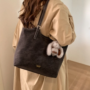 Detail of vintage brown tote bag with contrast stitching and plush rabbit charm