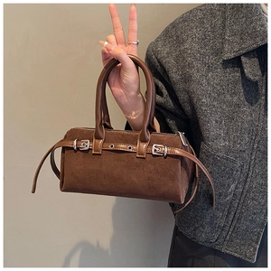 Detail of brown suede Boston bag featuring leather straps and silver metal buckles