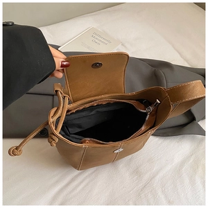 Detailed view of brown bucket bag with magnetic closure, lining and inner zip pocket