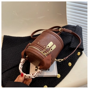 Close-up of vintage cylinder shoulder bag with silk scarf handle and gold zipper