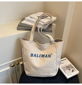 Detail shot of beige cotton canvas tote bag featuring premium blue embroidered BALIMAN logo