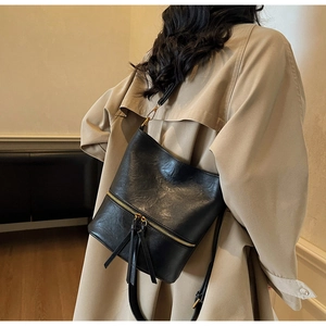 Détail du sac seau noir en similicuir avec fermetures éclair dorées et franges