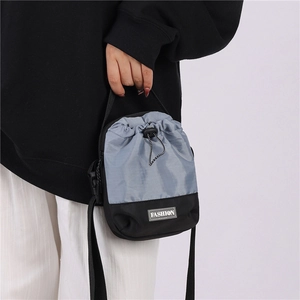 Detail van tweekleurige crossbodytas met trekkoord, modelabel en een verstelbare schouderriem