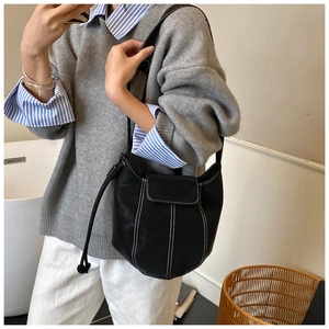 Detailed view of black bucket bag with white contrast stitching and soft leather texture