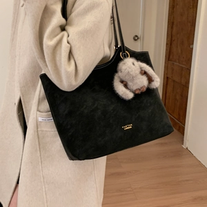 Detail of black suede tote bag with white stitching and grey plush bunny charm