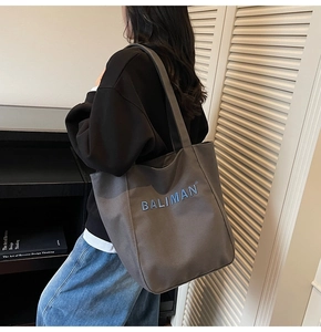 Detailed embroidery of BALIMAN logo on a large grey-brown canvas tote shoulder bag