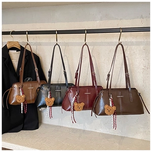 Close-up of four chic handbags in brown, black, burgundy, and dark coffee with bear charms