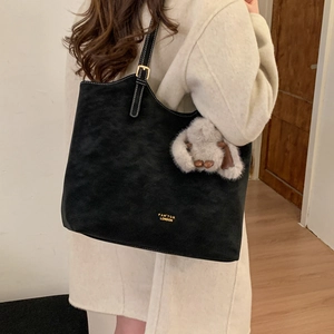 Detail of black tote bag with white contrast stitching and grey plush bunny charm