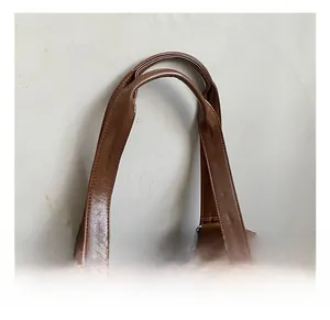 Macro view of brown glossy leather bag showing the wide handle and metal ring connector
