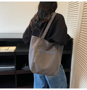 Detail showing high-capacity grey canvas tote bag with BALIMAN logo embroidery