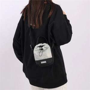 Outdoor crossbody mini tas met trekkoordsluiting en modieuze patch op de schouder