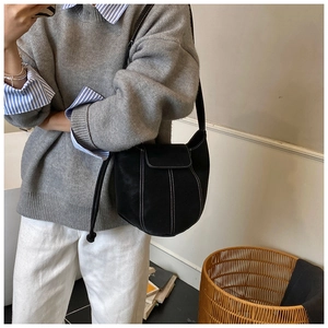 Detail view of black bucket bag with white contrast stitching and matte texture finish