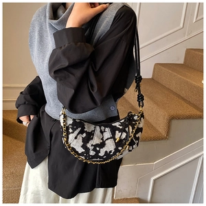 Detail of contrast pattern handbag with chunky gold chain strap on model in stairs
