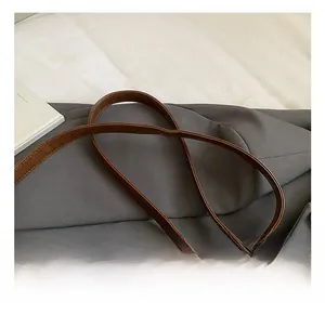 Detail shot of vintage brown leather tote showing the adjustable shoulder strap and metal buckle