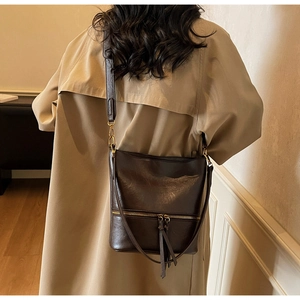 Détail d'un sac seau vintage marron foncé avec fermetures à pompons et large bandoulière