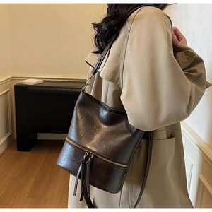 Détail du sac seau vintage marron foncé avec fermeture éclair dorée et glands décoratifs