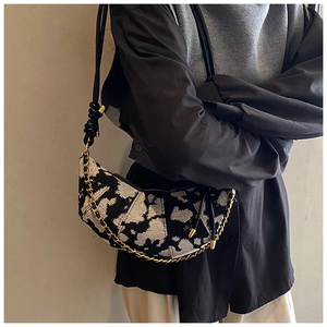 Close-up of crescent bag with black and white jacquard pattern and gold chain strap