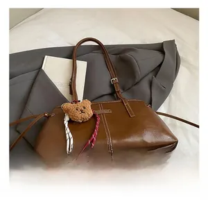 Detail of vintage brown faux leather handbag with contrast stitching and bear charm