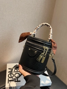 Black cylinder shoulder bag with leopard scarf and gold hardware in hand display