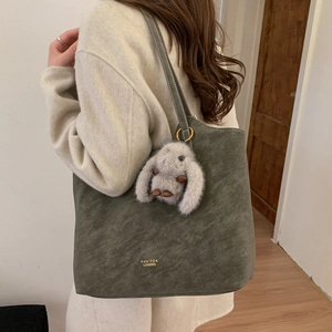 Detailed side view of large olive green tote bag with cute grey bunny charm on shoulder