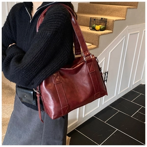 Detail of burgundy PU leather tote bag showing crossbody strap and reinforced side stitching