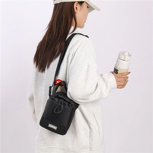 Detail van zwarte nylon crossbodytas met verstelbare riem en Fashion-label op persoon
