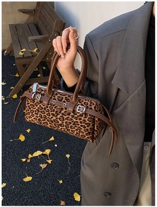 Detail of leopard print faux fur Boston bag held by model in autumn outdoor setting