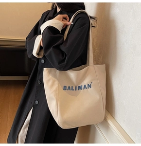 Detailed close-up of a large beige canvas tote bag with blue Baliman branding print