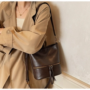 Détail du sac seau vintage marron foncé avec fermeture éclair dorée et franges en cuir